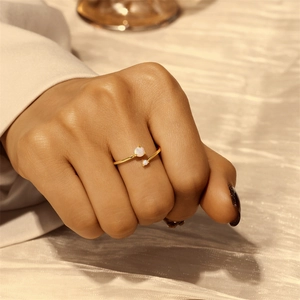 Detail of open gold ring featuring two milky white round stones on silk background
