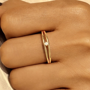 Detail of double-band gold ring with single diamond setting on silk fabric background