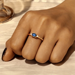Detailed view of an oval blue gemstone ring with side diamonds on a gold band