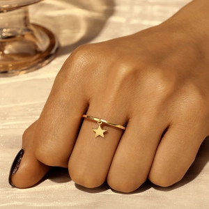 Detail of s925 silver gold-plated thin ring with delicate hanging star charm pendant