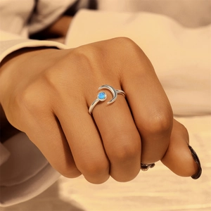 Detail of s925 silver crescent moon ring featuring a blue opal stone on a model's finger