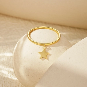 Detail of gold star pendant ring with delicate wavy texture on a minimalist background