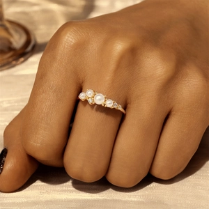 Detail of elegant gold double-layer ring with five white pearls and sparkling small diamonds
