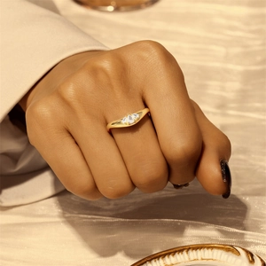 Close-up of gold slim ring with three teardrop-shaped white zircons on a model's finger