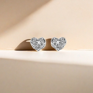 Macro shot of silver heart studs with pavé-set rose details and sparkling zircons