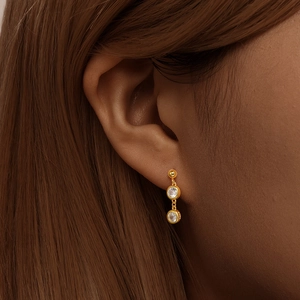 Close-up of elegant gold S925 silver earrings with two round clear cubic zirconia stones