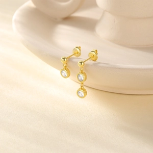Detail of asymmetric S925 silver gold-plated stud earrings with zircon stones