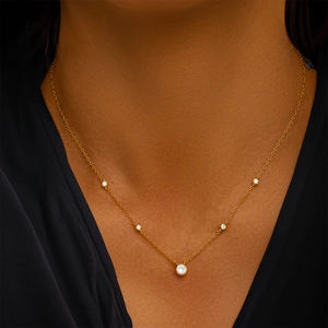 Detail of a minimalist gold necklace with five sparkling crystal pendants on model