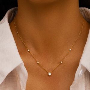Close-up of a delicate gold chain necklace with five bezel-set sparkling round crystals