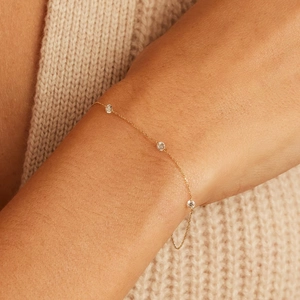 Detailed close-up of a minimalist gold S925 silver bracelet featuring three clear diamonds