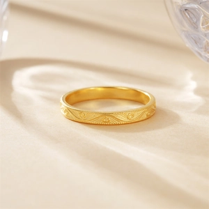 Makroaufnahme eines goldgravierten Rings mit Wellenmuster und feinen Perlenrand-Details
