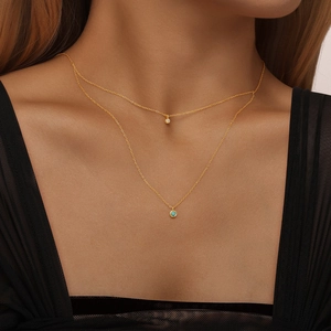 Nahaufnahme einer zweilagigen Silberkette mit Türkis und Glitzerstein am Model