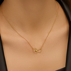 Close-up of gold s925 silver necklace with minimalist paw and heart charms on model