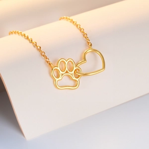 Macro shot of gold interlocking heart and paw print pendants on a dainty chain