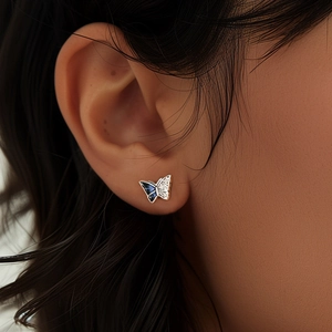 Gros plan détaillé d'une boucle d'oreille papillon en argent avec pierres bleues et diamants