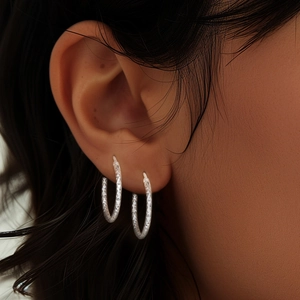 Detail of S925 silver hoop earrings with diamond-cut texture on female model