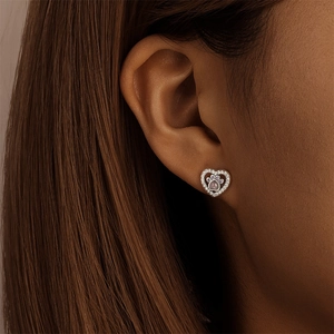 Gros plan de boucles d'oreilles cœur en argent avec patte de chat violette et zircons