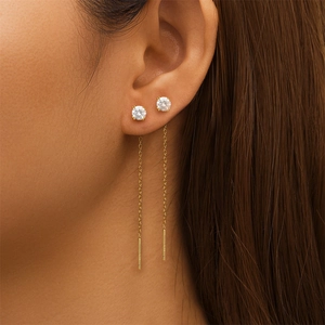 Detail showing gold tassel chain earrings with sparkling round cubic zirconia studs on ear