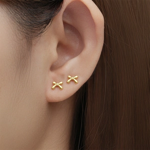 Nahaufnahme der matten goldenen Schleifenohrstecker am Ohr mit Doppelpiercing-Stil