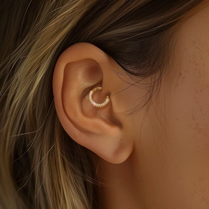 Dettaglio ravvicinato di un cerchio piercing in argento s925 dorato con zirconi incastonati