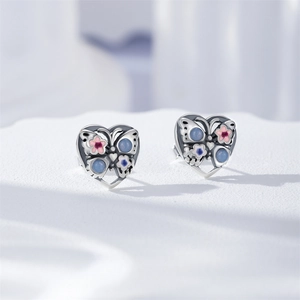 Vue détaillée de puces d'oreilles cœur en argent S925 avec papillon et fleurs émaillés