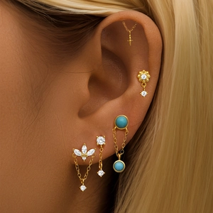 Detailopname van gouden oorset met turquoise steentjes en oorbellen met kettingen