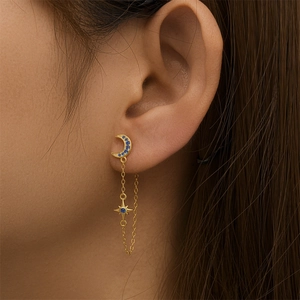 Detail of star and moon tassel earring in gold with blue crystals on model
