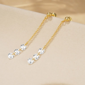 Detail view of long gold-plated tassel earrings with three sparkling round zircons