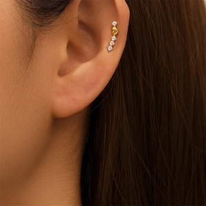Detailopname van gouden ear crawler met vier ronde zirkonia's en een kleine hartvormige bedel