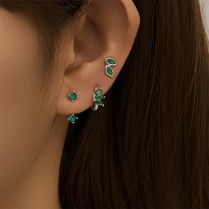Close-up of geometric S925 silver earrings set with sparkling green cubic zirconia stones