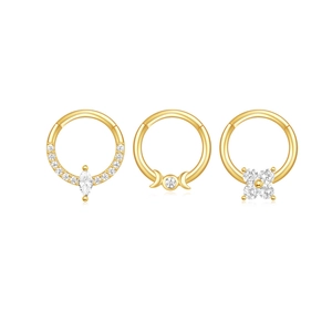 Dettaglio di tre anelli da setto placcati in oro con zirconi marquise e motivi lunari