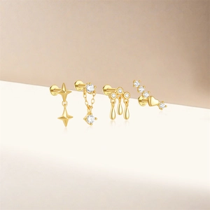Detail van vier gouden S925 zilveren oorknopjes met witte zirkonia en hangers met kwastjes