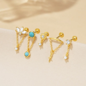 Detail van de 5-delige gouden piercingset met turquoise, zirkoon en kwastjesketting