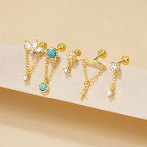 Detail van vijf gouden piercings met blauwe turkoois en witte zirkonia op display