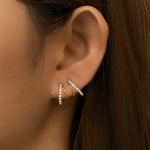 Macro view of three-layer gold wavy hoop earrings with paved shimmering zircons