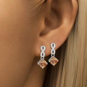 Dettaglio di orecchini infinity in argento S925 con gemme quadrate color champagne