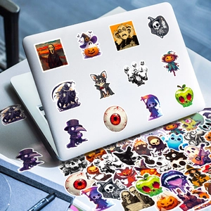Halloween-Sticker mit Ghostface und Kürbis auf einem silbernen Laptop und auf dem Tisch