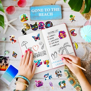Flat lay of waterproof cartoon stickers on a notebook with summer beach accessories