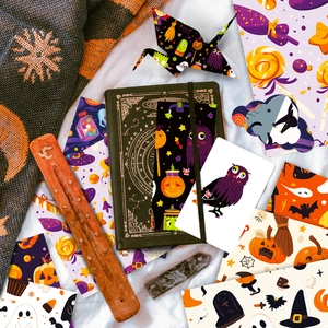 Flat lay of Halloween stationery set with dark green notebook, stickers and pumpkins