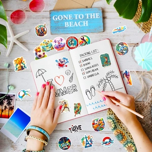 Flat lay of 2024 Paris sports themed stickers for luggage with beach vacation decor
