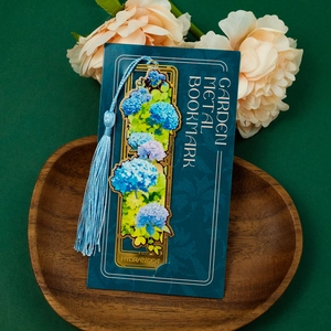 Detail of hollow brass hydrangea bookmark with blue tassel on a wooden tray