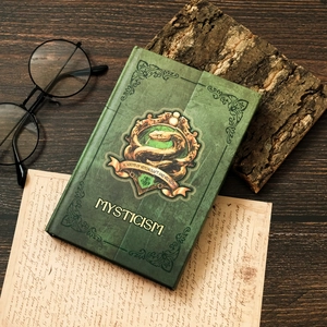 Detail of green vintage magic notebook with embossed gold snake totem on faux leather cover