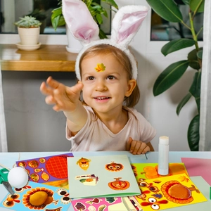 Detail of girl creating DIY Thanksgiving stickers with turkey and pumpkin motifs