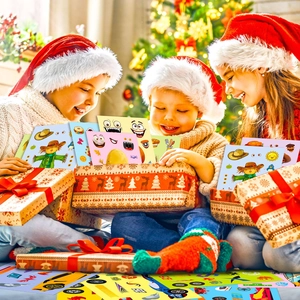 Three happy kids opening DIY sticker set gifts in front of a festive Christmas tree