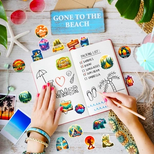 Flat lay of outdoor adventure stickers with travel notebook and summer vacation accessories