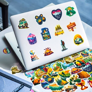 Detail of outdoor adventure stickers on a laptop featuring mountain and camping designs