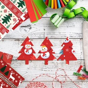 Detail of red Christmas tree paper tag with snowman pattern on white wood background