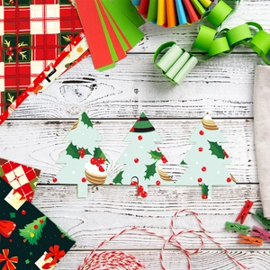 Flat lay of colorful Christmas tree paper cutouts with festive scrapbooking supplies