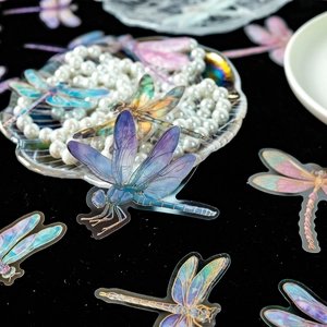 Vibrant 3D gold-foiled dragonfly PET stickers in purple and blue on black velvet