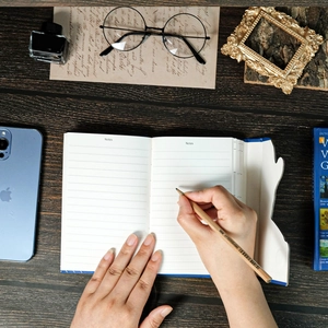 Close-up of lined notepad with Van Gogh art cover and wooden pencil on desk